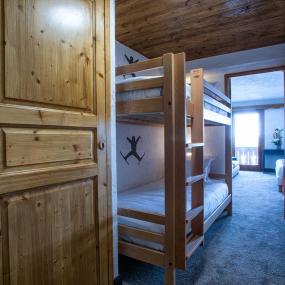 Porte ouverte sur une chambre familiale avec lits superposés dans l'hôtel Courcheneige à Courchevel