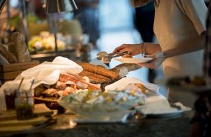 Une femme qui se sert sur le buffet du petit-déjeuner de l'hôtel Courcheneige