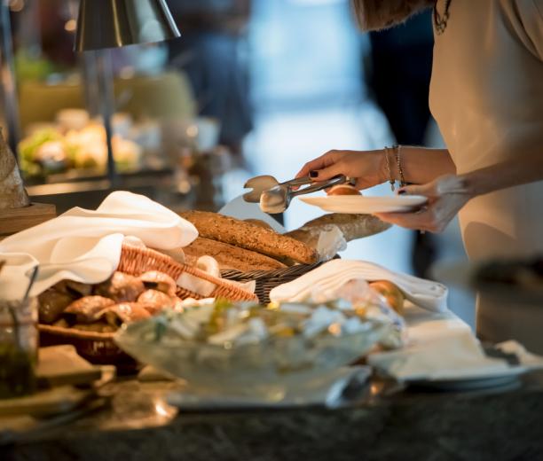 Une femme qui se sert sur le buffet du petit-déjeuner de l'hôtel Courcheneige