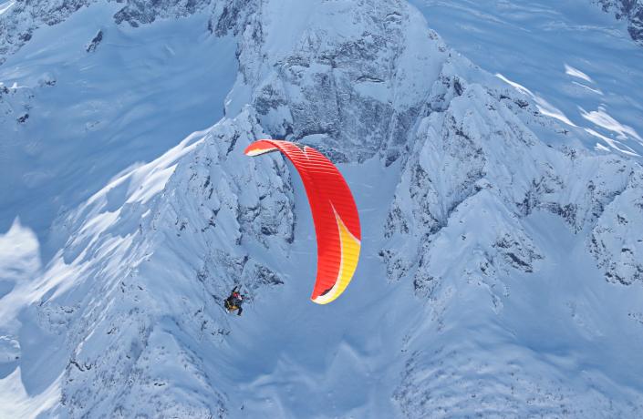 Une personne qui fait du parapente au dessus des montagnes enneigées