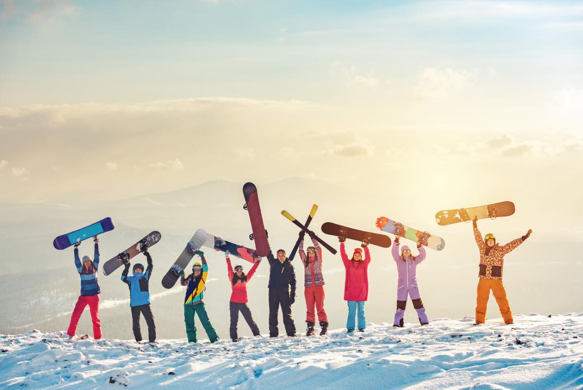 Famille dans la neige qui brandit des snowboards