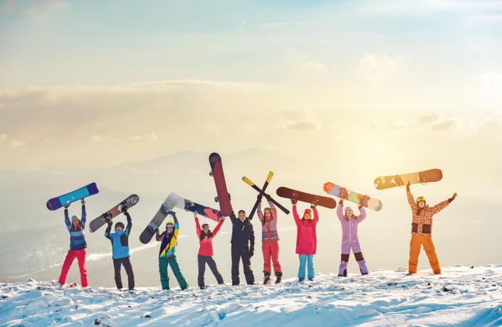 Famille dans la neige qui brandit des snowboards