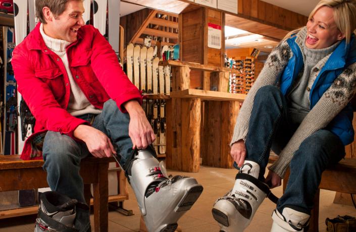 Un homme et une femme qui enfilent leurs chaussures de skis