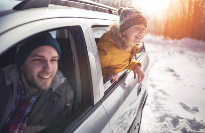 Un homme et un enfant qui passent la tête par la fenêtre de la voiture pour observer le paysage enneigé