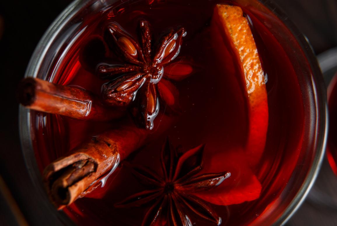 Gros plan sur un cocktail dans un verre avec des tiges de cannelles et une tranche d'orange au Courcheneige