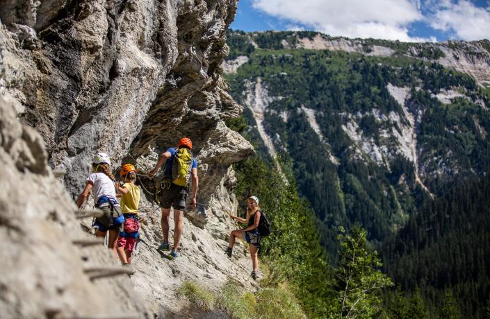 Famille qui fait de l'escalade à flan de falaise à Courchevel en été