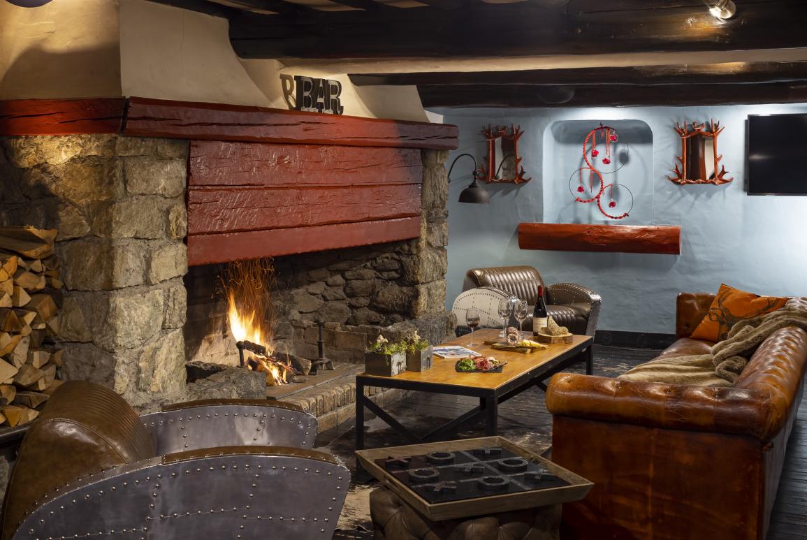 Salon avec cheminée et canapé en cuir de l'hôtel Courcheneige à Courchevel