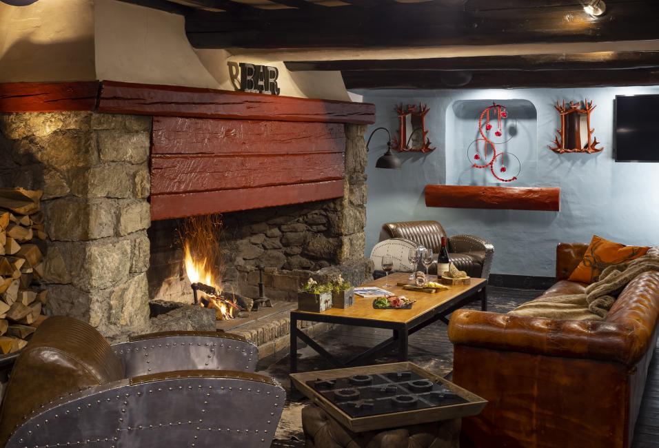 Salon avec cheminée et canapé en cuir de l'hôtel Courcheneige à Courchevel