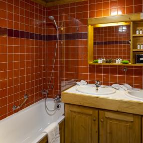 Salle de bains avec baignoire aux tons oranges dans la chambre familiale du Courcheneige