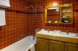 Salle de bains avec baignoire aux tons oranges dans la chambre familiale du Courcheneige