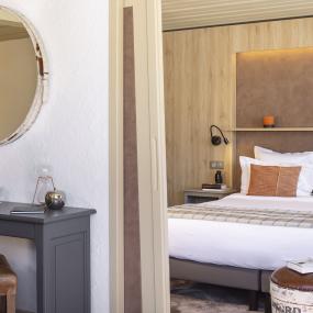 Salon d'une suite donnant sur la chambre avec grand lit double dans l'hôtel Courcheneige