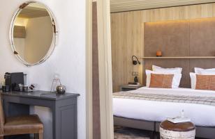 Salon d'une suite donnant sur la chambre avec grand lit double dans l'hôtel Courcheneige